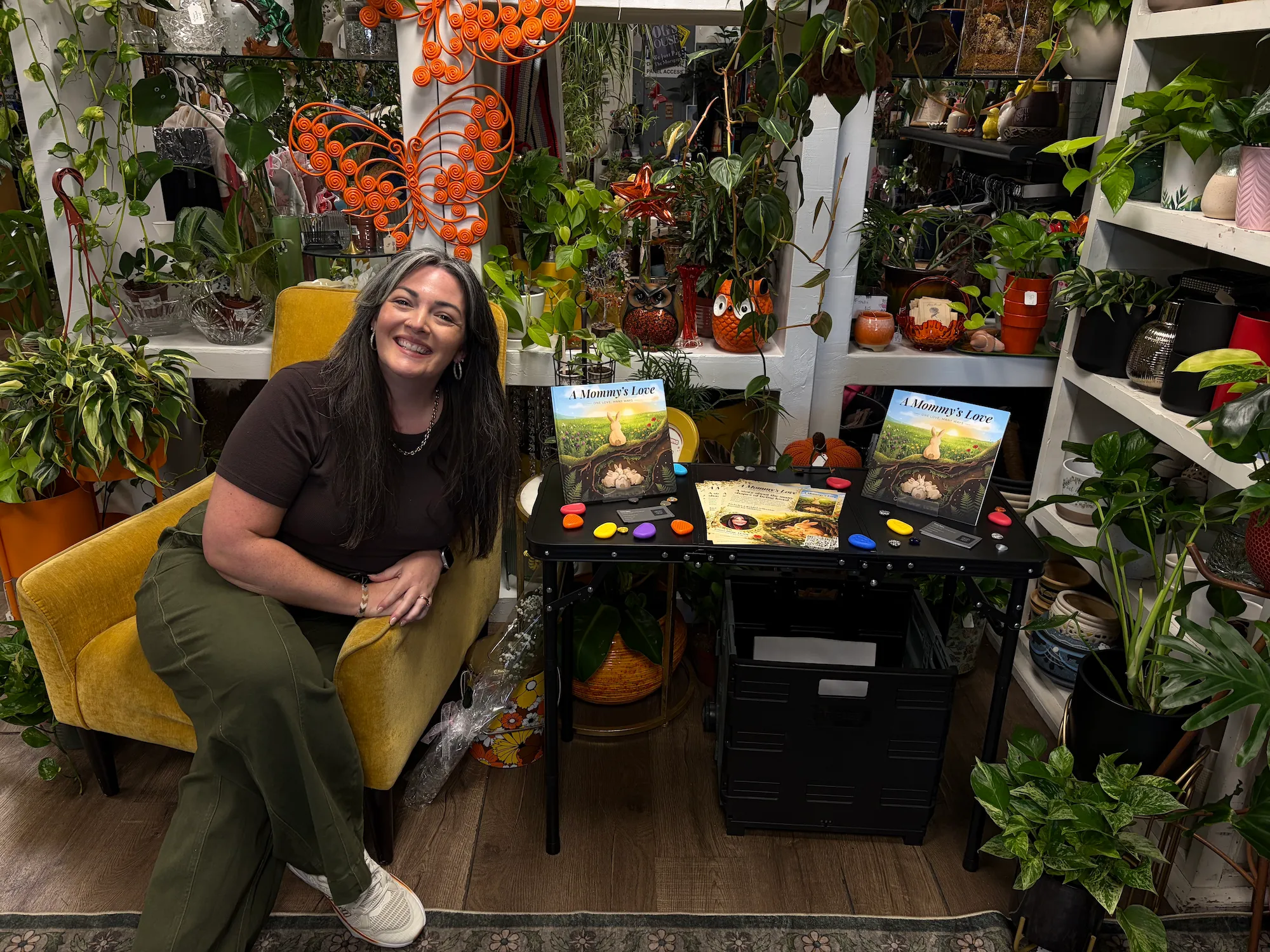 Greer Dear at her book-signing table surrounded by plants
